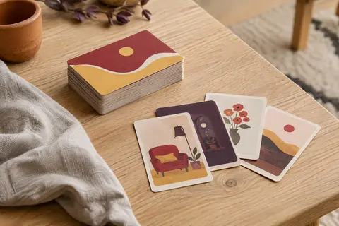 Cartes d’un jeu d’enquête de poche aux accents rouges et jaunes, posées sur une table en bois clair.