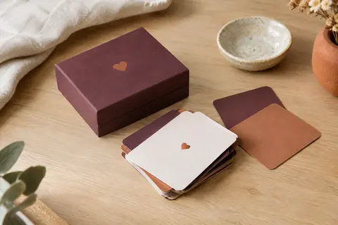 Petit jeu de questions pour couples et cartes posés sur une table en bois clair dans un intérieur accueillant.